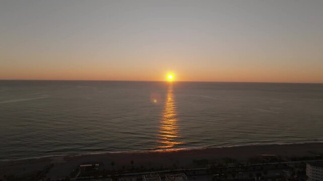 Drone view rising from the densely built city of Mahmutlar to a pathway lit by the sunset over the sea