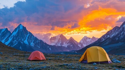 Colorful tents stand against a majestic mountain backdrop as the sun sets, casting warm hues across the sky. The tranquil campsite invites adventure and exploration in nature's embrace