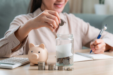 Asian woman hand put coins in piggy bank,Saving money wealth and financial concept. 