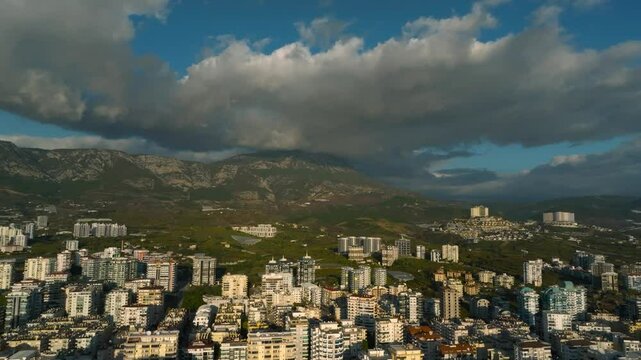 Drone view above residential buildings towards the mountain peak shrouded in clouds in Mahmutlar, Turkey