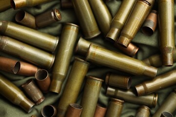 Many used rifle cartridges on military camo green fabric background