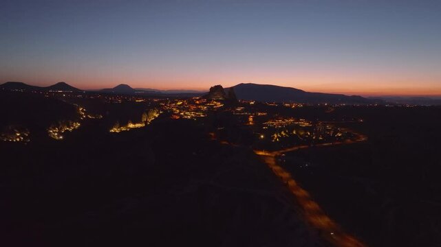 Drone view of the illuminated Uchisar Castle at dusk during sunset in Cappadocia
