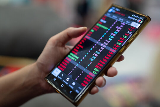 Action of a businessman is using mobilephone to review, chart analyse or trading during money or stock crisis loss situation. Financial tranding concept scene. Extreme close-up with soft focus.