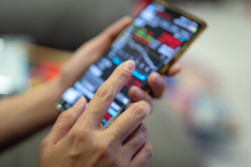 Action of a businessman is using mobilephone to review, chart analyse or trading during money or stock crisis loss situation. Financial tranding concept scene. Extreme close-up with soft focus.