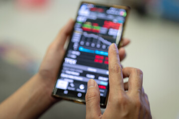 Action of a businessman is using mobilephone to review, chart analyse or trading during money or stock crisis loss situation. Financial tranding concept scene. Extreme close-up with soft focus.