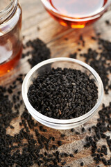 Black cumin seed oil in a glass bowl, with Nigella oil in the background