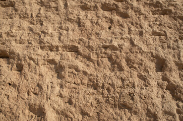 Ancient weathered adobe wall plastered with mud closeup