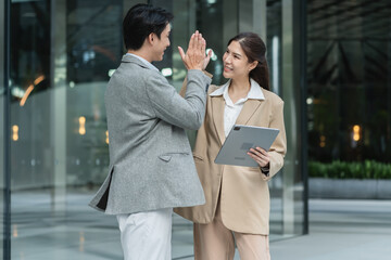Cheerful successful asian business colleagues giving high five at outdoor office...