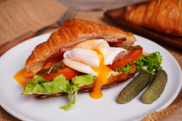 Croissant bread and poached eggs, vegetables and ham Breakfast on the table