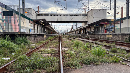 Naklejka premium Train line in the suburbs of the metropolis of Sao Paulo in Brazil with a station in the background.