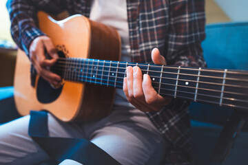 Close-up of a musician playing an acoustic guitar, fingers pressing on the fretboard, evoking a sense of creativity, passion, and emotional connection through warm, resonant tones