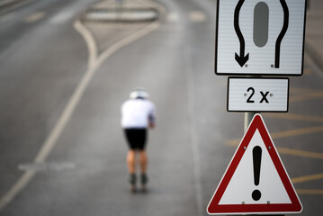 Traffic sign on the road, defocused roller skiing in tuck position