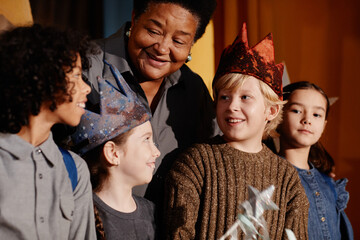 Diverse group of children smiling and celebrating under guidance of an adult during a festive...
