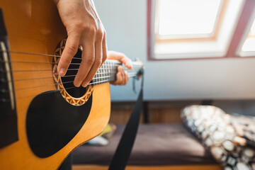 Close-up perspective of an acoustic guitar being played, with fingers pressing the fretboard,...