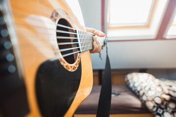 Fototapeta premium Close-up perspective of an acoustic guitar being played, with fingers pressing the fretboard, capturing the warmth of natural wood, the resonance of the strings. Indoor music