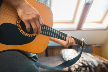 Close-up perspective of an acoustic guitar being played, with fingers pressing the fretboard,...