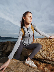 Young woman in sporty attire climbing a rock, showcasing determination and strength against a...