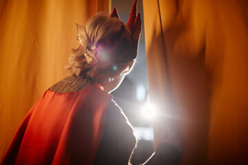 Person wearing a stage costume peeking through the curtains, illuminated by a bright light....