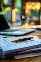 Elegant Fountain Pen Resting on Documents in Sunlit Office Setting with Blurred Background of Laptop and Warm Ambient Lighting