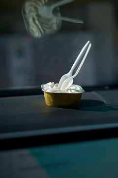 Pastry cup with plastic spoons on a car dashboard in the sunlight, Florida Keys, USA