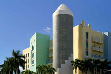 Colorful Art Deco building with a cylindrical glass block tower and palm trees under a blue sky, Miami, Florida, USA