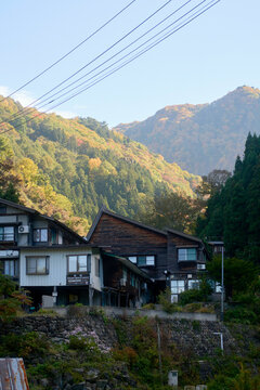 Rustic houses nestled in a lush mountain landscape under a clear sky, Japanese Alps