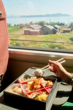 Bento box on train with scenic countryside and lake views outside the window, near Kanazawa, Japan