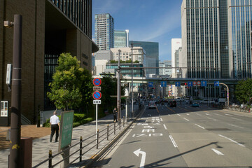 Busy urban street with skyscrapers, pedestrians, road signs, and clear blue sky. Osaka, Japan