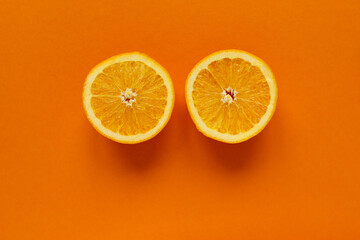 round slice of fresh orange fruit like big eyes on orange background