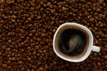 small white cup of black coffee with coffee beans 