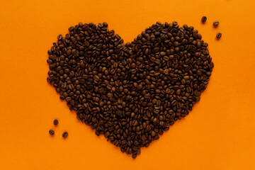 aroma coffee beans in the heart shape on orange background