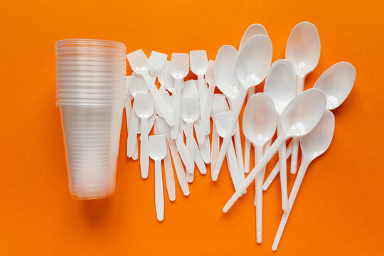 white plastic disposable cutlery on orange bachground (tablespoons, teaspoons, cups)
environmental problem 