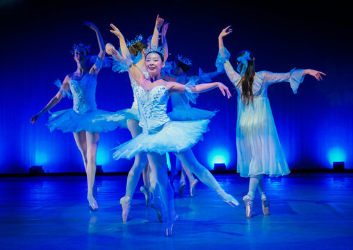Ballet dancers in white tutus perform gracefully under dramatic stage lighting, The Nutcracker, Bainbridge Island, USA