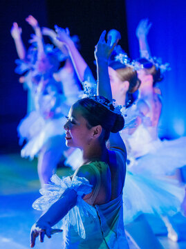 Ballet dancers in elegant blue costumes perform on stage under dramatic lighting. The Nutcracker, Bainbridge Island, USA