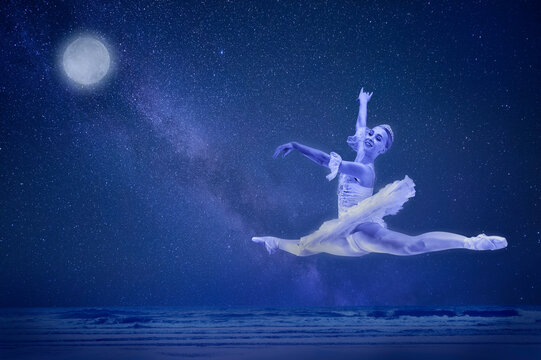 Ballerina in a white tutu gracefully leaps against a starry night sky with a full moon. The Nutcracker, Bainbridge Island, USA