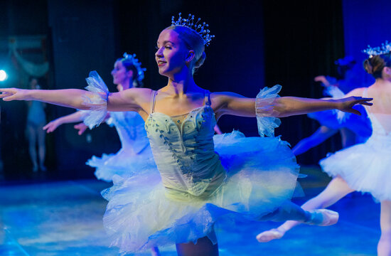 Ballerinas in blue tutus perform gracefully on a dimly lit stage. The Nutcracker, Bainbridge Island, USA