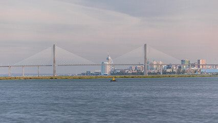 Vasco da Gama Bridge over river Tagus timelapse in Lisbon with park of Nations district modern architecture, Portugal