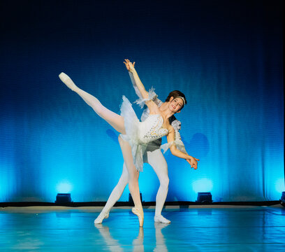 Ballet dancers perform a graceful duet on stage under vibrant blue lighting. The Nutcracker, Bainbridge Island, USA