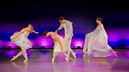 Four ballet dancers in colorful costumes performing on a stage with purple lighting. The Nutcracker, Bainbridge Island, USA