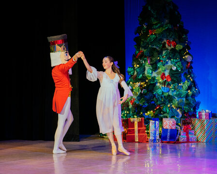 Nutcracker ballet performance with a dancer and child on stage near a decorated Christmas tree. The Nutcracker, Bainbridge Island, USA