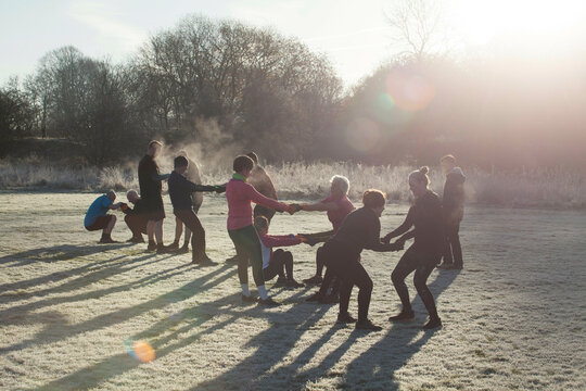 A group of people engaged in outdoor exercise on a frosty morning, forming a circle and holding hands, Sale Water Park, Manchester, UK