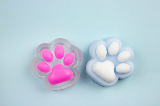 Cute colorful cat paw shape squishy jelly slime toys on blue background, studio shot, copy space. Modern popular sensory toy concept.