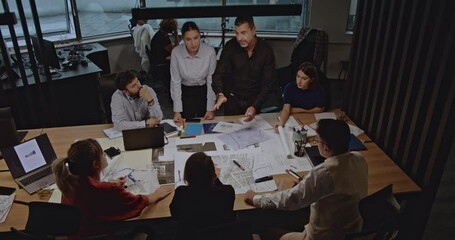 Diverse business team collaborating on project plans in a modern office. Discussing blueprints and strategies in a productive meeting. - Powered by Adobe