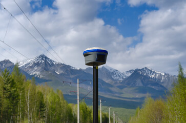 GNSS receiver during geodetic survey among trees and mountains
