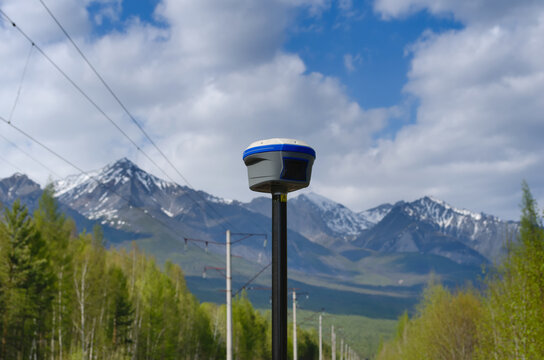 GNSS receiver during geodetic survey among trees and mountains