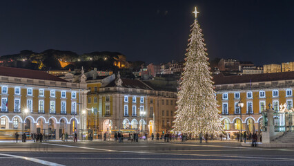 Naklejka premium Commerce Square in Lisbon illuminated at Christmas hyperlapse, with a towering tree and crowds celebrating at night. Portugal