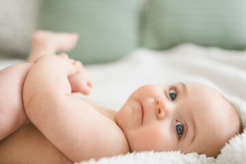 Laughing baby girl on white bedroom