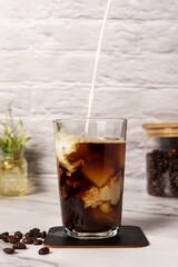 glass of iced coffee with milk pour