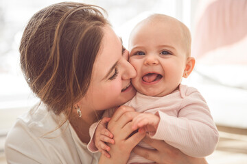 Cute small baby girl in bed at home. Woman holding little infant child.