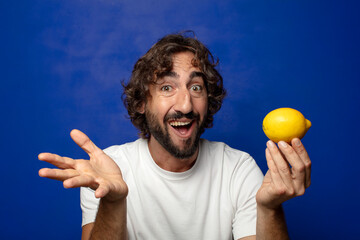 young adult bearded man holding a lemon